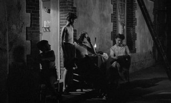 Movie still from “Jacquot of Nantes” (1991), directed by Agnès Varda – A group of people sitting around a table with a lit candle; Wide shot, High angle