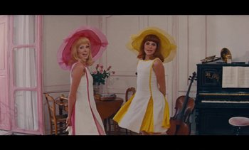 Movie still from “Jacquot of Nantes” (1991), directed by Agnès Varda – A couple of women wearing dresses and hats; Medium shot, Low angle