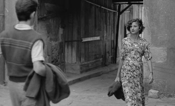 Movie still from “Jacquot of Nantes” (1991), directed by Agnès Varda – An old photo of a woman walking down the street; Medium shot, Over the shoulder angle