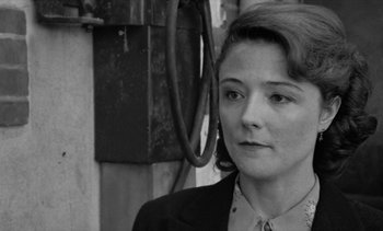 Movie still from “Jacquot of Nantes” (1991), directed by Agnès Varda – Black and white photograph of a woman in a suit; Close Up shot, Over the shoulder angle