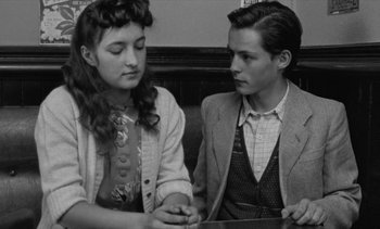 Movie still from “Jacquot of Nantes” (1991), directed by Agnès Varda – A young man and a young woman sitting at a table; Medium shot, High angle