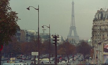 Movie still from “Jacquot of Nantes” (1991), directed by Agnès Varda – A view of the eiffel tower from a busy street corner; Extreme Wide shot, Low angle