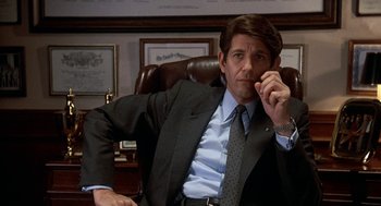 Movie still from “Jagged Edge” (1985), directed by Richard Marquand – A man in a suit and tie sitting in a chair; Close Up shot, Low angle