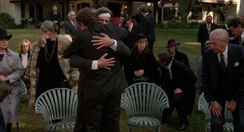 Movie still from “Jagged Edge” (1985), directed by Richard Marquand – A group of people sitting around a lawn with chairs; Wide shot, Over the shoulder angle