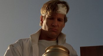 Movie still from “Jagged Edge” (1985), directed by Richard Marquand – A man with a bandage on his head looking down at a jar; Close Up shot, Low angle