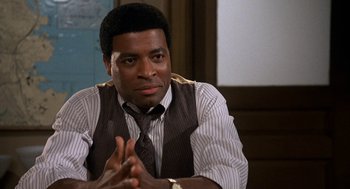 Movie still from “Jagged Edge” (1985), directed by Richard Marquand – A man in a vest and tie clasping his hands; Close Up shot, High angle