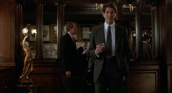 Movie still from “Jagged Edge” (1985), directed by Richard Marquand – A man in a suit holding a glass of wine; Medium shot, Low angle