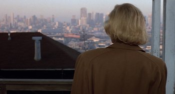 Movie still from “Jagged Edge” (1985), directed by Richard Marquand – A woman looking out over a city from a balcony; Close Up shot, Over the shoulder angle