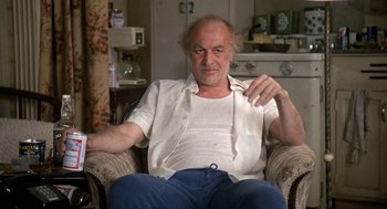 Movie still from “Jagged Edge” (1985), directed by Richard Marquand – An older man sitting in a chair in a living room; Medium shot, Low angle