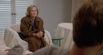 Movie still from “Jagged Edge” (1985), directed by Richard Marquand – A woman sitting on a chair in front of a man; Medium shot, Over the shoulder angle