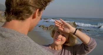 Movie still from “Jagged Edge” (1985), directed by Richard Marquand – A man and a woman on the beach looking at each other; Close Up shot, Over the shoulder angle