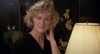 Movie still from “Jagged Edge” (1985), directed by Richard Marquand – A woman with blonde curly hair posing for a picture; Close Up shot, Over the shoulder angle