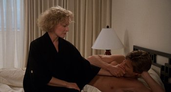 Movie still from “Jagged Edge” (1985), directed by Richard Marquand – A man laying on a bed with a woman in front of him; Close Up shot, Low angle