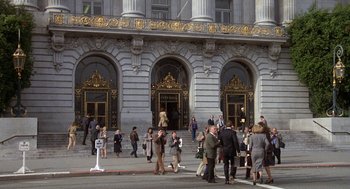 Movie still from “Jagged Edge” (1985), directed by Richard Marquand – A group of people walking down a street near a building; Extreme Wide shot, High angle