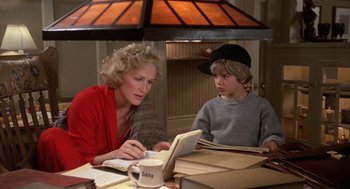 Movie still from “Jagged Edge” (1985), directed by Richard Marquand – A woman sitting at a table with a young boy; Medium shot, High angle