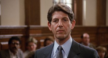 Movie still from “Jagged Edge” (1985), directed by Richard Marquand – A person wearing a suit and tie; Close Up shot, Low angle