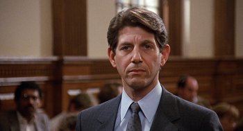 Movie still from “Jagged Edge” (1985), directed by Richard Marquand – A person wearing a suit and tie; Close Up shot, Low angle