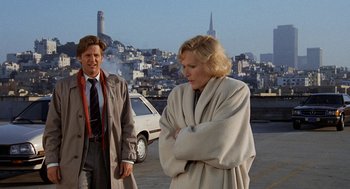 Movie still from “Jagged Edge” (1985), directed by Richard Marquand – A man and a woman standing next to each other in a parking lot; Medium shot, Low angle