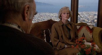 Movie still from “Jagged Edge” (1985), directed by Richard Marquand – An older man and a woman sitting on a couch; Medium shot, Over the shoulder angle