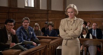 Movie still from “Jagged Edge” (1985), directed by Richard Marquand – A woman standing in front of a jury in a court room; Medium shot, Over the shoulder angle