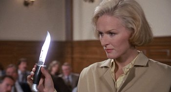 Movie still from “Jagged Edge” (1985), directed by Richard Marquand – A woman holding a knife up to her face; Close Up shot, Low angle