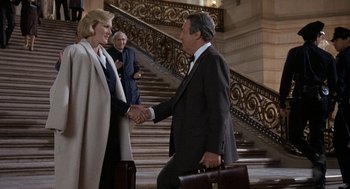 Movie still from “Jagged Edge” (1985), directed by Richard Marquand – A man and a woman shaking hands in front of a staircase; Medium shot, Over the shoulder angle