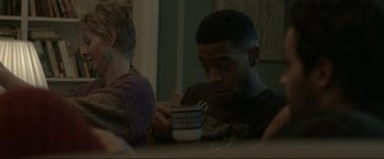 Movie still from “James White” (2015), directed by Josh Mond – A man sitting at a table with a cell phone in front of him; Medium shot, Over the shoulder angle