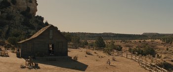 Movie still from “Jane Got a Gun” (2015), directed by Gavin O'Connor – A person standing in a field near a house; Extreme Wide shot, High angle