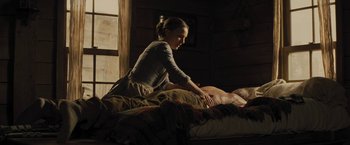 Movie still from “Jane Got a Gun” (2015), directed by Gavin O'Connor – A woman sitting on top of a bed next to a man; Medium shot, Low angle