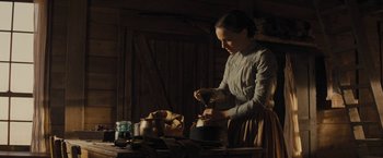 Movie still from “Jane Got a Gun” (2015), directed by Gavin O'Connor – A woman is pouring something into a pot; Medium shot, Low angle