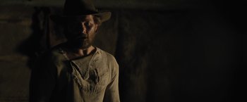 Movie still from “Jane Got a Gun” (2015), directed by Gavin O'Connor – A man with a beard wearing a cowboy hat; Medium shot, Over the shoulder angle