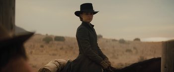Movie still from “Jane Got a Gun” (2015), directed by Gavin O'Connor – A woman riding a horse in the middle of a field; Medium shot, Low angle