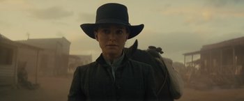 Movie still from “Jane Got a Gun” (2015), directed by Gavin O'Connor – A woman wearing a black hat and a green jacket; Medium shot, Low angle