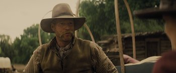 Movie still from “Jane Got a Gun” (2015), directed by Gavin O'Connor – A man with a cowboy hat and vest on; Close Up shot, Over the shoulder angle