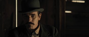 Movie still from “Jane Got a Gun” (2015), directed by Gavin O'Connor – A man with a mustache wearing a hat and a jacket; Close Up shot, Low angle