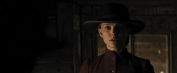 Movie still from “Jane Got a Gun” (2015), directed by Gavin O'Connor – A woman wearing a hat standing in front of a wooden wall; Close Up shot, Low angle