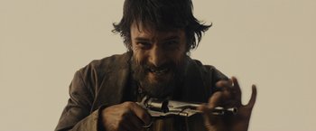 Movie still from “Jane Got a Gun” (2015), directed by Gavin O'Connor – A man with long hair and a beard holding a gun; Close Up shot, Low angle