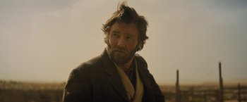 Movie still from “Jane Got a Gun” (2015), directed by Gavin O'Connor – A person wearing a suit and tie; Close Up shot, Over the shoulder angle