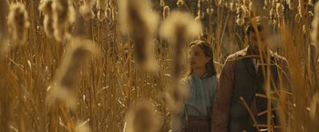 Movie still from “Jane Got a Gun” (2015), directed by Gavin O'Connor – A woman standing next to a field of tall grass; Medium shot, Low angle