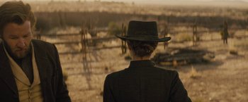 Movie still from “Jane Got a Gun” (2015), directed by Gavin O'Connor – A woman wearing a cowboy hat looking out over a field of cacti; Medium shot, Over the shoulder angle