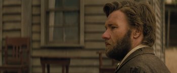 Movie still from “Jane Got a Gun” (2015), directed by Gavin O'Connor – A person with a beard looking to the side; Close Up shot, Over the shoulder angle