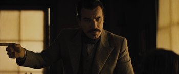 Movie still from “Jane Got a Gun” (2015), directed by Gavin O'Connor – A man with a mustache wearing a suit and tie; Close Up shot, Low angle
