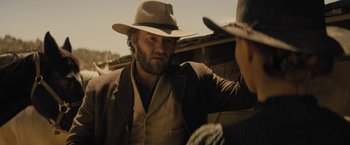 Movie still from “Jane Got a Gun” (2015), directed by Gavin O'Connor – A man with a hat and a beard standing next to another man in a cowboy hat; Medium shot, Over the shoulder angle