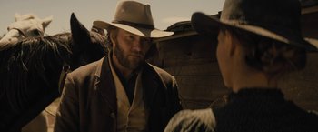 Movie still from “Jane Got a Gun” (2015), directed by Gavin O'Connor – A man wearing a cowboy hat talking to another man; Close Up shot, Over the shoulder angle