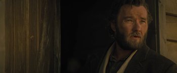 Movie still from “Jane Got a Gun” (2015), directed by Gavin O'Connor – A man with a beard is looking out of a window; Close Up shot, Over the shoulder angle