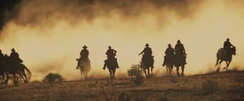 Movie still from “Jane Got a Gun” (2015), directed by Gavin O'Connor – A group of men riding horses through a dusty field; Extreme Wide shot, Low angle