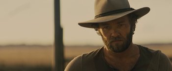 Movie still from “Jane Got a Gun” (2015), directed by Gavin O'Connor – A person wearing a hat; Close Up shot, Over the shoulder angle