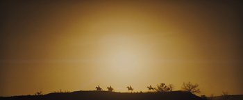 Movie still from “Jane Got a Gun” (2015), directed by Gavin O'Connor – A group of people riding horses on top of a hill at sunset; Extreme Wide shot, Low angle