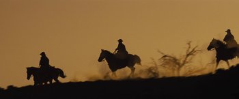 Movie still from “Jane Got a Gun” (2015), directed by Gavin O'Connor – A man riding on the back of a brown horse; Extreme Wide shot, Low angle