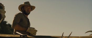 Movie still from “Jane Got a Gun” (2015), directed by Gavin O'Connor – A man in a hat and gloves holding a knife; Close Up shot, Low angle